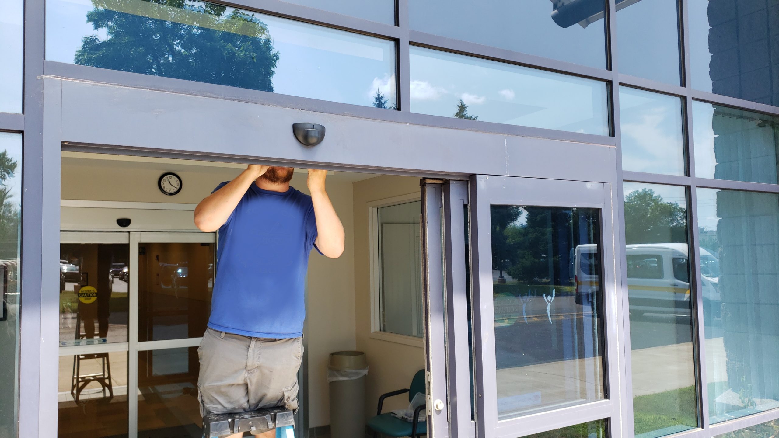 A 24 Hour Door Technician repairing operator on automatic sliding glass door