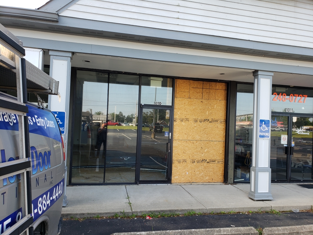 Broken storefront glass with wooden boardup
