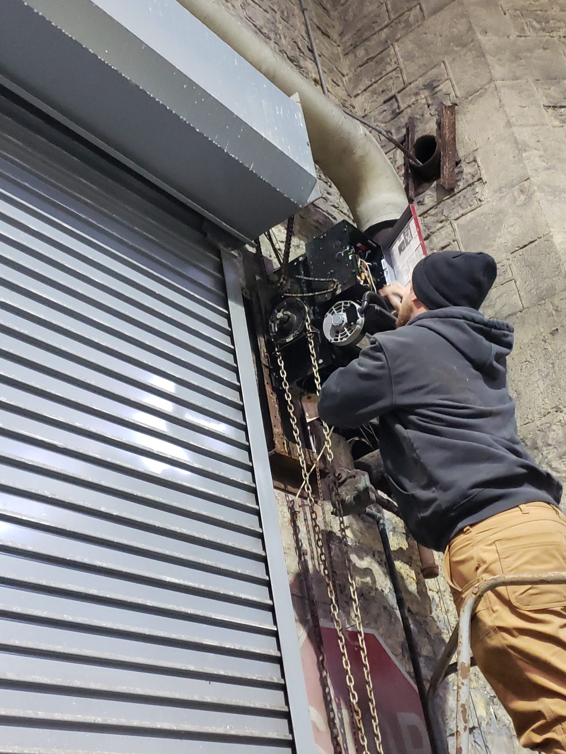 A 24 Hour Door Service technician repairing the operator on a commercial overhead door.