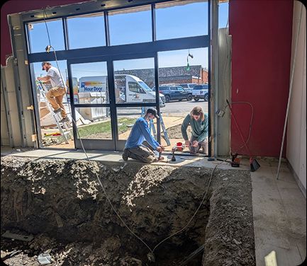 Technicians installing a storefront glass commercial door in Cincinnati, OH, with an A 24 Hour Door service van visible outside.