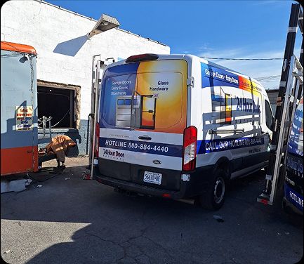 A 24 Hour Door service van in Cincinnati, OH with a technician performing on-site commercial door repair at a local facility.